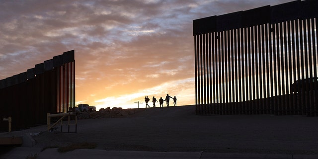 Un par de familias migrantes de Brasil atraviesan un hueco en el muro fronterizo para llegar a Estados Unidos después de cruzar de México a Yuma, Arizona, para buscar asilo.