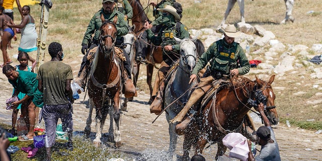 Oficiales montados de Aduanas y Protección Fronteriza de Estados Unidos intentan contener a los migrantes mientras cruzan el Río Grande desde Ciudad Acuña, México, hacia Del Rio, Texas, el domingo 19 de septiembre de 2021.