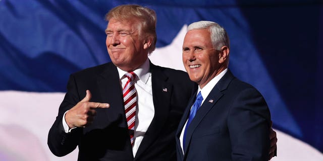 Donald Trump y Mike Pence posan juntos en un escenario. 