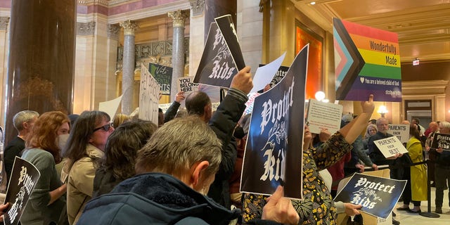 Manifestantes sostienen carteles mientras corean a favor y en contra de un proyecto de ley que haría de Minnesota un estado de refugio trans