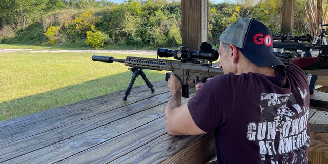 Un hombre ataviado con material de Gun Owners of America dispara un rifle