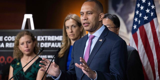 El líder de la minoría demócrata en la Cámara de Representantes, Hakeem Jeffries, habla en un podio con otros miembros del liderazgo demócrata de la Cámara de Representantes de pie junto a él.